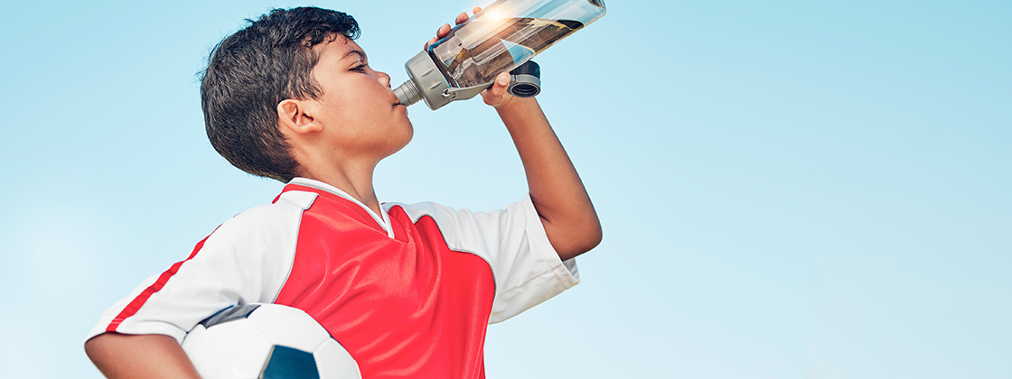 Niño futbolista bebiendo agua